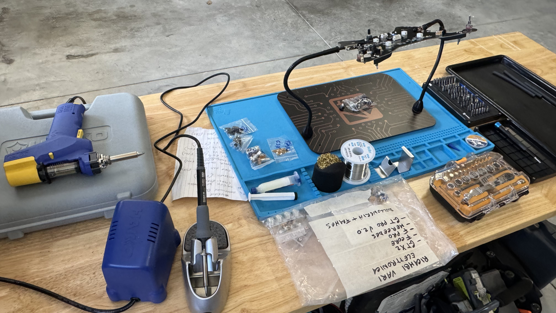 Cube Controls wheel electronics on a repair workbench with soldering tools and labeled replacement parts